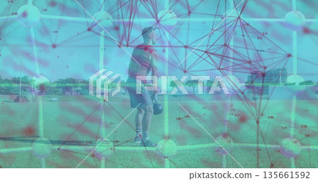 Performing kettlebell squat mid adult male in workout clothes on grassy field, with yellow poles 135661592