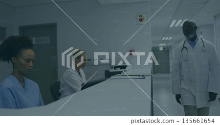 Collaborating medical team typing at hospital reception desk with monitor, keyboard and stethoscope 135661654