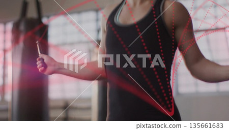 Gripping jump rope handles, woman in sportswear jumping at gym with punching bags, red dotted lines 135661683