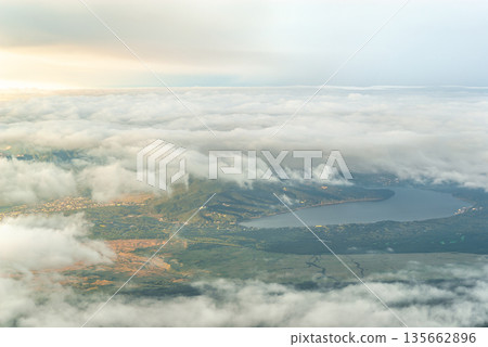 A calm morning view of Lake Yamanaka and Yamanakako Village seen through a sea of clouds from the hiking trail near the seventh station of Mount Fuji A calm morning view of Lake Yamanaka and Yamanakako Village seen through a sea of clouds from the hiking trail near the seventh station of Mount Fuji 135662896