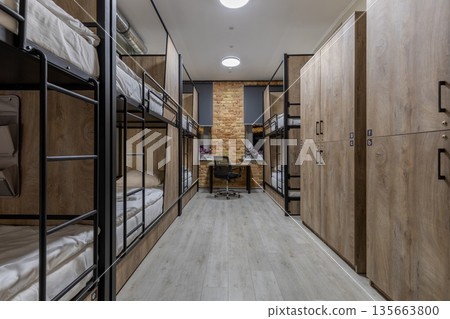 Symmetrical loft hostel dormitory with bunk beds and wooden lockers Symmetrical loft hostel dormitory with bunk beds and wooden lockers 135663800