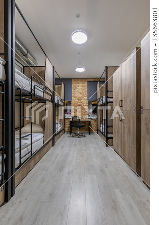 Symmetrical vertical shot of a loft hostel dormitory with bunk beds and wooden lockers 135663801