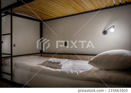 Close-up of a neat bunk bed in a loft hostel with warm lighting 135663805