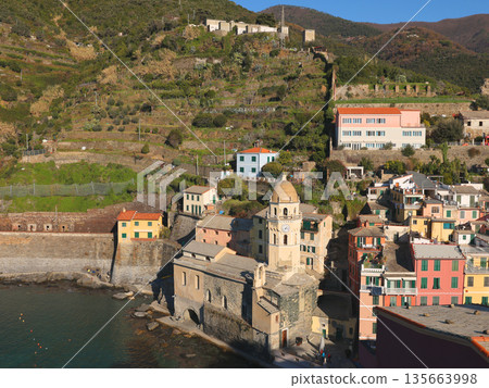 View of Vernazza, a town in Cinque Terre, from the mountain. Nature and sea, traditional buildings of Liguria, Italy. Architecture protected by UNESCO. Church of Santa Margherita. 135663998