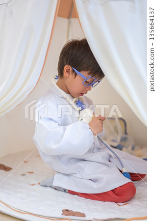 Young Boy Pretending To Be A Doctor In A Play Tent Environment Young Boy Pretending To Be A Doctor In A Play Tent Environment 135664137