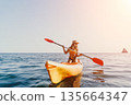 Kayaking Woman Ocean - A woman paddling a yellow kayak in the ocean on a sunny day. 135664347