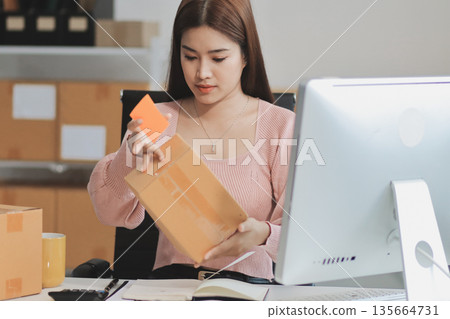 Starting small businesses SME owners female entrepreneurs check online orders to prepare to pack the boxes, sell to customers, sme business ideas online. Starting small businesses SME owners female entrepreneurs check online orders to prepare to pack the boxes, sell to customers, sme business ideas online. 135664731