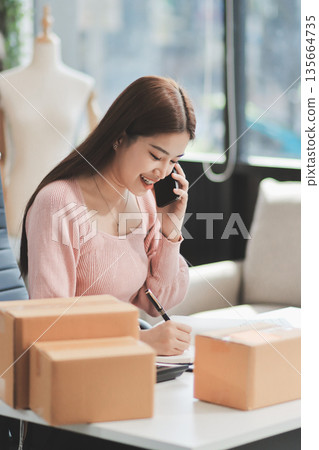 Starting small businesses SME owners female entrepreneurs check online orders to prepare to pack the boxes, sell to customers, sme business ideas online. Starting small businesses SME owners female entrepreneurs check online orders to prepare to pack the boxes, sell to customers, sme business ideas online. 135664735