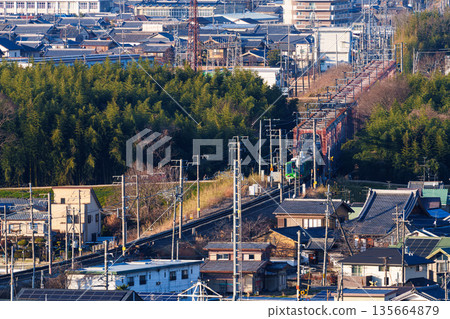 A JR Nara Line train crossing the Kizugawa River bridge. View from Shiroyamadai Castle Ruins Park, Kizugawa City, Kyoto Prefecture. 135664879