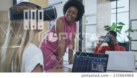 Facilitator in pink dress leaning on table guiding VR headset users in meeting room showing charts Facilitator in pink dress leaning on table guiding VR headset users in meeting room showing charts 135664968