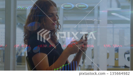 Examining charts on phone, woman in black top sitting inside glass-partitioned office, copy space Examining charts on phone, woman in black top sitting inside glass-partitioned office, copy space 135664982