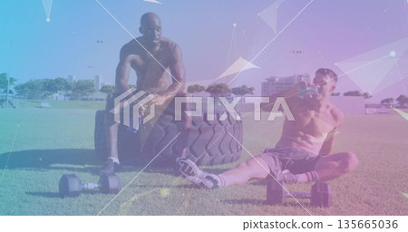 Resting shirtless workout partners taking break on grassy field, with tractor tire and dumbbells Resting shirtless workout partners taking break on grassy field, with tractor tire and dumbbells 135665036