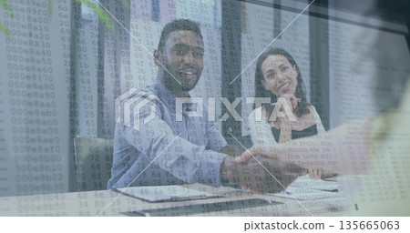 Exchanging handshake, colleagues sitting in office at glass table with laptop and code overlay 135665063