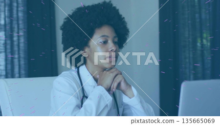 Focusing female doctor wearing white coat examining laptop screen in clinic, featuring stethoscope Focusing female doctor wearing white coat examining laptop screen in clinic, featuring stethoscope 135665069
