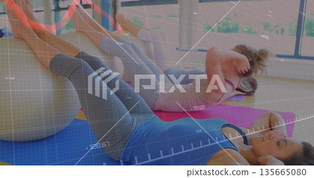 Balancing women in sportswear doing abs and leg lifts in fitness studio, with stability balls 135665080