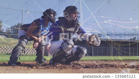 Crouching catchers holding mitts at baseball home plate, with helmets and chest protectors 135665121