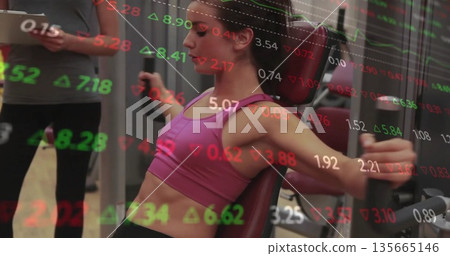 Pushing chest press grips woman in sportswear in gym with tablet-holding trainer and ticker overlay 135665146