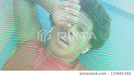 Lying fitness enthusiast wiping forehead sweat on blue mat at gym, wearing earbuds stripe overlay Lying fitness enthusiast wiping forehead sweat on blue mat at gym, wearing earbuds stripe overlay 135665160