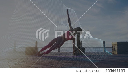 Woman holding side plank pose in sportswear on stone pier at sunrise, with mat, block, railing Woman holding side plank pose in sportswear on stone pier at sunrise, with mat, block, railing 135665165