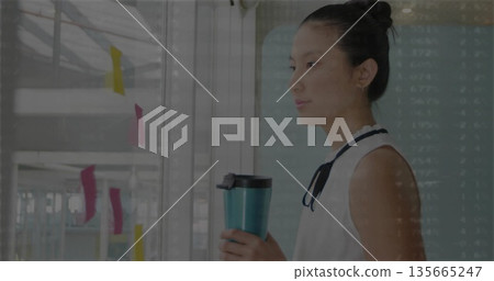 Planning midadult Asian holding teal mug beside whiteboard with sticky-notes in office, copy space 135665247