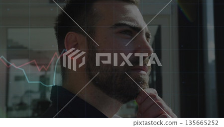 Analyzing businessman wearing blazer resting chin at glass office window, with red and blue charts 135665252