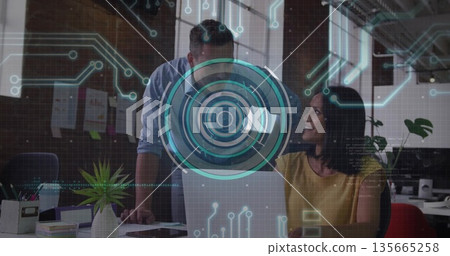 Collaborating male and female coworkers reviewing data on laptop at office desk with HUD overlay Collaborating male and female coworkers reviewing data on laptop at office desk with HUD overlay 135665258