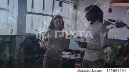 Collaborating woman wearing work attire with laptop and man with tablet working in open-plan office Collaborating woman wearing work attire with laptop and man with tablet working in open-plan office 135665264