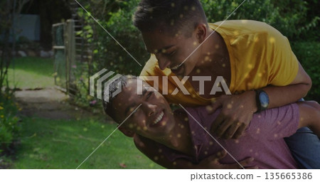 Sharing piggyback ride wearing plum polo, friend wearing yellow tee, wristwatch at garden gate Sharing piggyback ride wearing plum polo, friend wearing yellow tee, wristwatch at garden gate 135665386