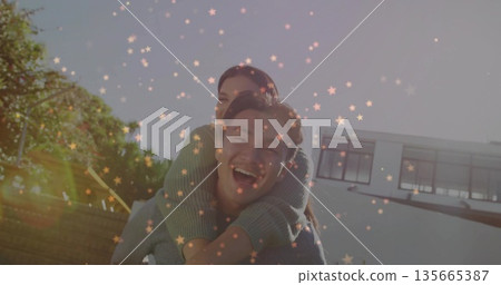 Laughing Korean man giving piggyback ride to woman in modern white house backyard, with lens flares Laughing Korean man giving piggyback ride to woman in modern white house backyard, with lens flares 135665387
