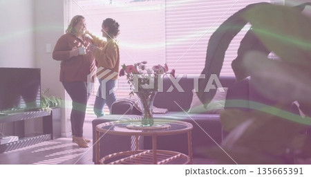 Chatting friends holding white mugs and adjusting hair in living room with coffee table, copy space Chatting friends holding white mugs and adjusting hair in living room with coffee table, copy space 135665391
