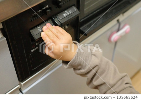 A toddler touching the switch on a gas stove in the kitchen 135665624