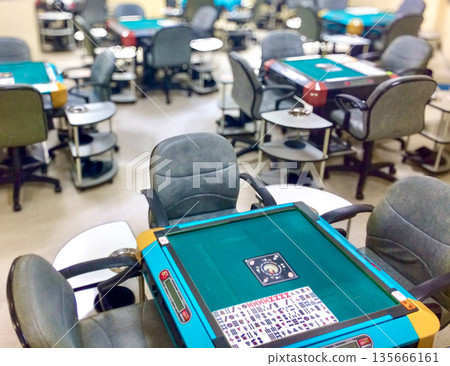 Inside a Japanese mahjong parlor, with many mahjong tables lined up 135666161