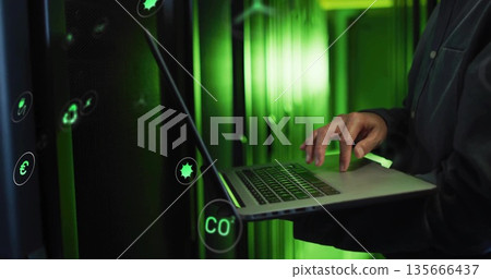 IT technician typing on laptop in data center, with server racks, green LEDs, icons, copy space 135666437