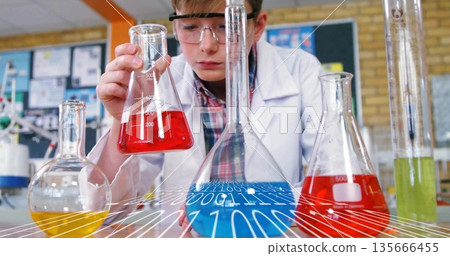 Examining red liquid in conical flask, boy wearing lab coat and goggles at school lab Examining red liquid in conical flask, boy wearing lab coat and goggles at school lab 135666455
