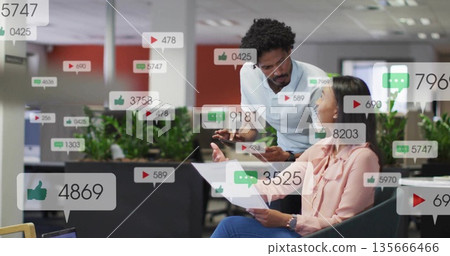 Reviewing colleagues discussing social media metrics in corporate lounge, with tablet and reports Reviewing colleagues discussing social media metrics in corporate lounge, with tablet and reports 135666466