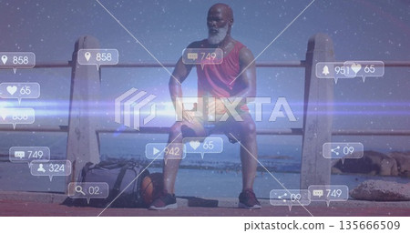 Sitting man wearing smartwatch on seaside promenade, with duffle bag, basketball, floating icons Sitting man wearing smartwatch on seaside promenade, with duffle bag, basketball, floating icons 135666509