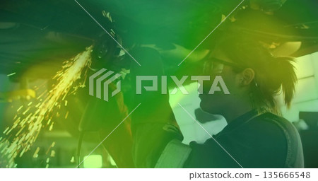 Grinding mechanic using angle grinder under chassis in shop with gloves, safety glasses, copy space Grinding mechanic using angle grinder under chassis in shop with gloves, safety glasses, copy space 135666548