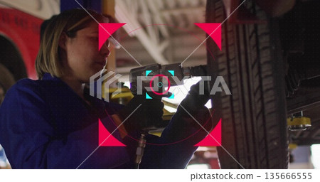 Removing lug nuts coverall-clad mechanic using air impact wrench on tire in service bay, copy space Removing lug nuts coverall-clad mechanic using air impact wrench on tire in service bay, copy space 135666555