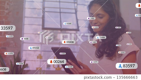 Smiling woman in pink blouse holding tablet and gazing at notifications in loft studio, copy space Smiling woman in pink blouse holding tablet and gazing at notifications in loft studio, copy space 135666663