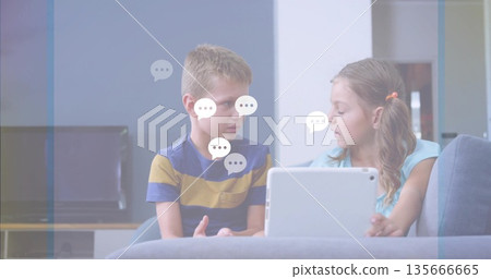 Showing brother and sister interacting with tablet on gray sofa in living room, with TV Showing brother and sister interacting with tablet on gray sofa in living room, with TV 135666665