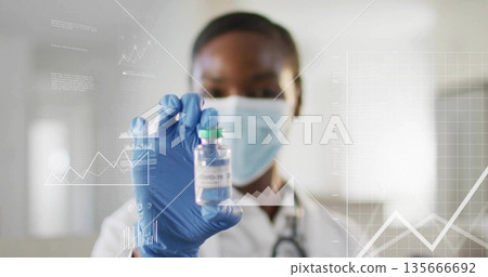 Holding researcher wearing mask and gloves analyzing chart data in hospital lab, with COVID-19 vial 135666692