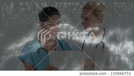 Nurse in scrubs and doctor in lab coat examining folder of records in clinic, with stethoscopes Nurse in scrubs and doctor in lab coat examining folder of records in clinic, with stethoscopes 135666753