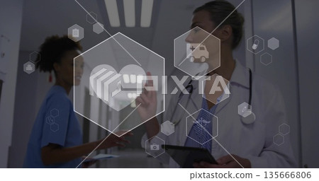 Interacting female doctor manipulating icons in midair with tablet in hospital hallway, copy space 135666806
