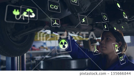 Female mechanic in jumpsuit draining oil, inspecting car underside in garage, with lift, eco icons 135666844