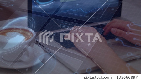 Typing hands on laptop computer at wooden desk, with coffee cup and holographic HUD overlays 135666897