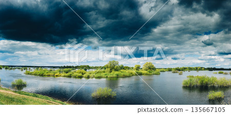 Countryside Landscape During Spring Flood Floodwaters. Bold Bright Blue Sky Above Nature Landscape During Spring Flood. Amazing Reflections In River. Musical Calmness Concept. Tranquil View Countryside Landscape During Spring Flood Floodwaters. Bold Bright Blue Sky Above Nature Landscape During Spring Flood. Amazing Reflections In River. Musical Calmness Concept. Tranquil View 135667105