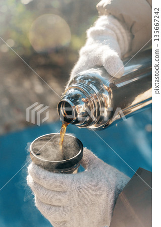 Coffee Pouring from Thermos into Cup on a Sunny Winter Day Coffee Pouring from Thermos into Cup on a Sunny Winter Day 135667242