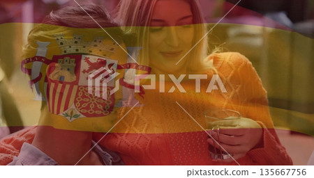 Sitting couple sharing moment in home living room, with clear glass mug and Spanish flag overlay Sitting couple sharing moment in home living room, with clear glass mug and Spanish flag overlay 135667756