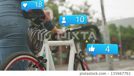 Denim-jacket cyclist viewing notifications on white bicycle with cable lock on sidewalk, copy space Denim-jacket cyclist viewing notifications on white bicycle with cable lock on sidewalk, copy space 135667761