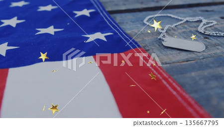 Showing American flag draping over wooden tabletop with dog tags and gold star confetti, copy space Showing American flag draping over wooden tabletop with dog tags and gold star confetti, copy space 135667795